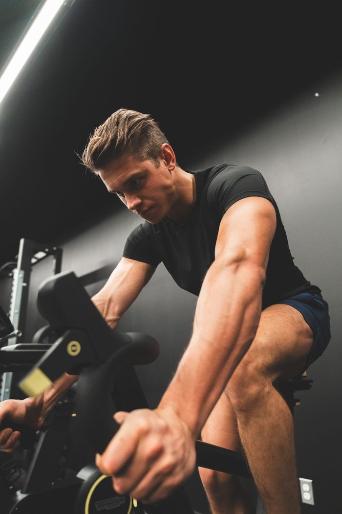 Home Fit young man intensely cycling on a stationary bike indoors.