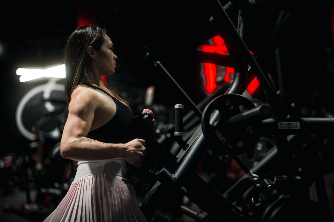 Focused woman engaging in a strength training session at the gym using robust fitness machinery.
